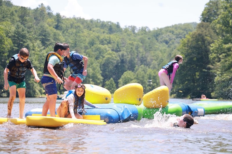 Campers playing on floating toys in a lake
